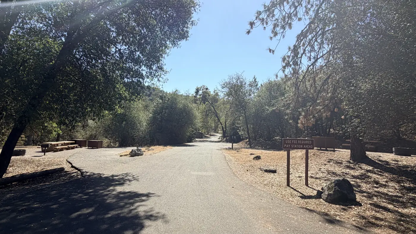 Campground road past picnic tables, with a "Use fee required, pay station ahead" sign